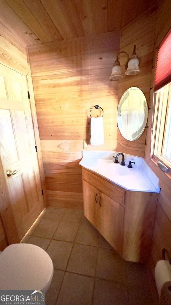 bathroom with tile patterned flooring, toilet, wooden walls, wood ceiling, and vanity