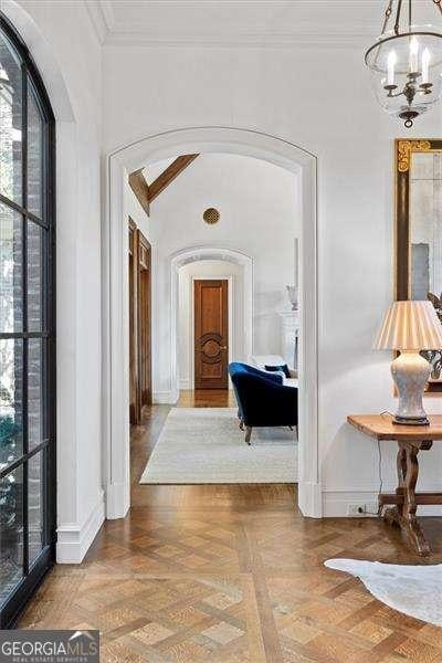 hall featuring parquet flooring, an inviting chandelier, and ornamental molding