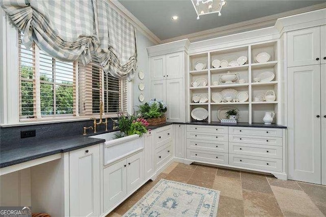 kitchen with crown molding, white cabinets, and sink