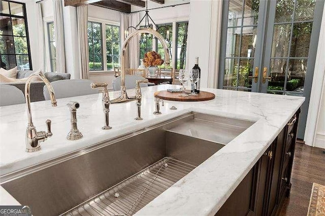 details with french doors, light stone counters, dark brown cabinetry, and sink