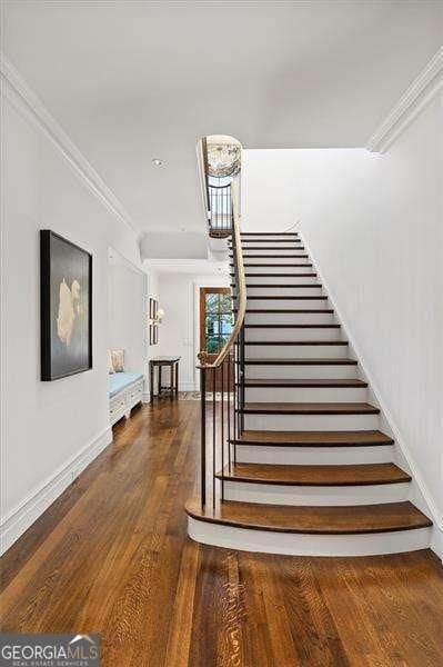 stairway with crown molding and hardwood / wood-style flooring