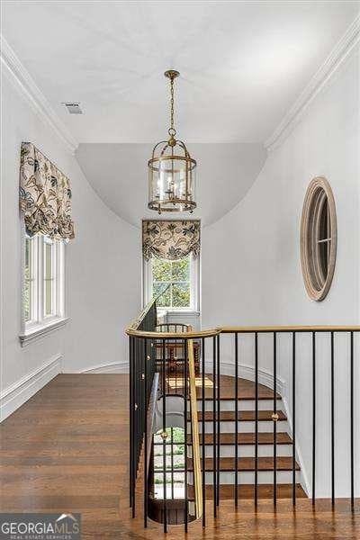 stairway featuring hardwood / wood-style flooring, a chandelier, and ornamental molding