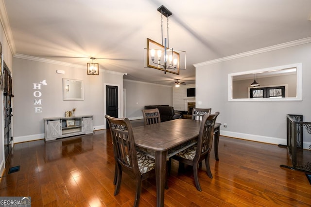 dining space featuring ornamental molding, dark hardwood / wood-style floors, an inviting chandelier, and a fireplace