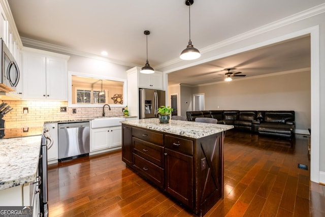 kitchen featuring pendant lighting, appliances with stainless steel finishes, backsplash, white cabinets, and a kitchen island