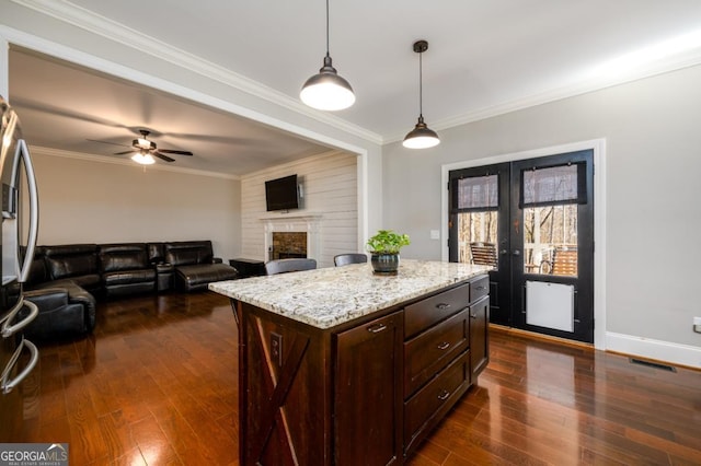 kitchen featuring crown molding, decorative light fixtures, a center island, and a brick fireplace