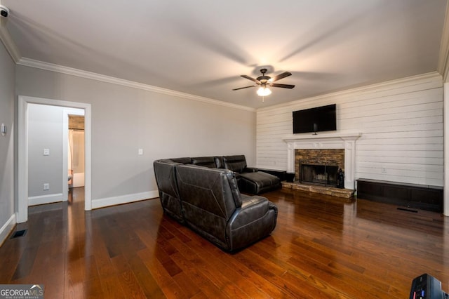 living room with dark wood-type flooring, ornamental molding, and a fireplace