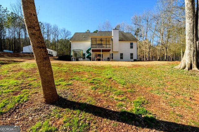 rear view of house featuring a yard and a sunroom