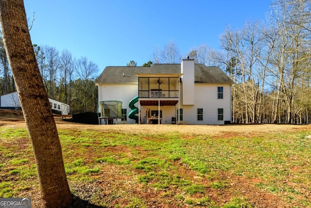 rear view of property with ceiling fan, a sunroom, and a lawn