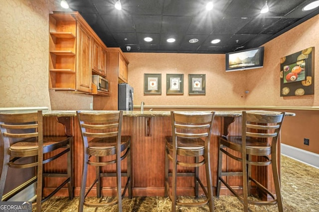 bar with a paneled ceiling and stainless steel appliances