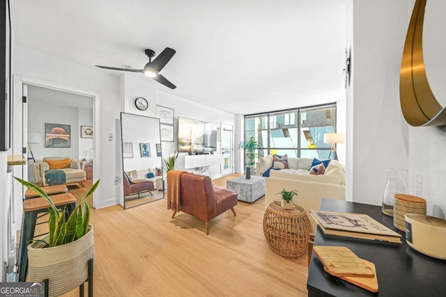 living room with ceiling fan, expansive windows, and light hardwood / wood-style flooring