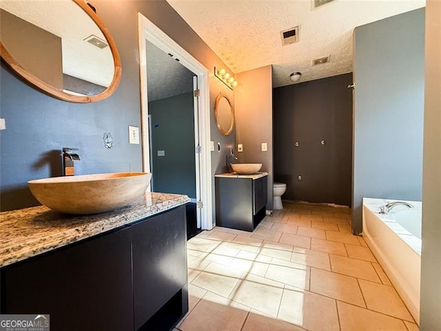 bathroom with a textured ceiling, tile patterned floors, vanity, a bathtub, and toilet