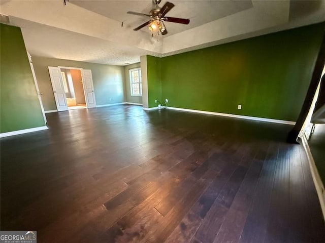 spare room with ceiling fan, dark hardwood / wood-style flooring, and a raised ceiling