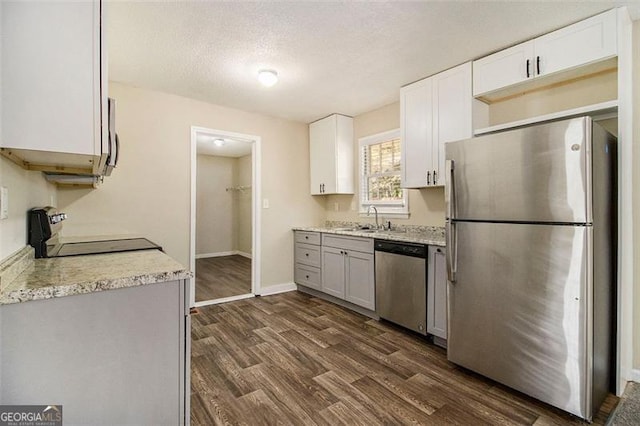 kitchen with dark wood-type flooring, appliances with stainless steel finishes, and white cabinetry