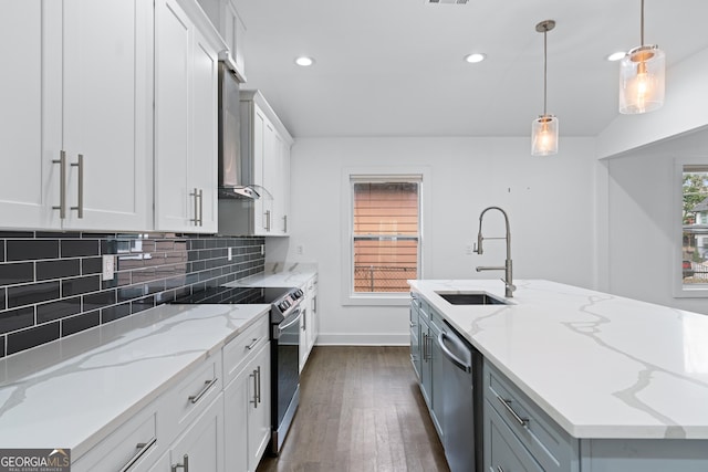 kitchen featuring a kitchen island with sink, sink, stainless steel appliances, and white cabinets