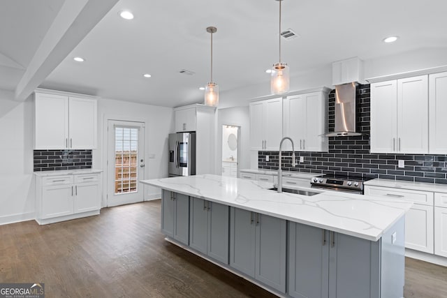 kitchen featuring white cabinetry, appliances with stainless steel finishes, wall chimney exhaust hood, and a center island with sink