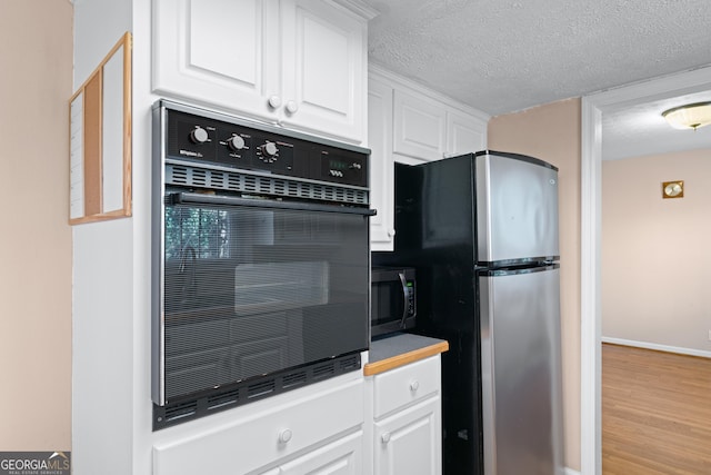 kitchen with white cabinetry, appliances with stainless steel finishes, a textured ceiling, and light wood-type flooring