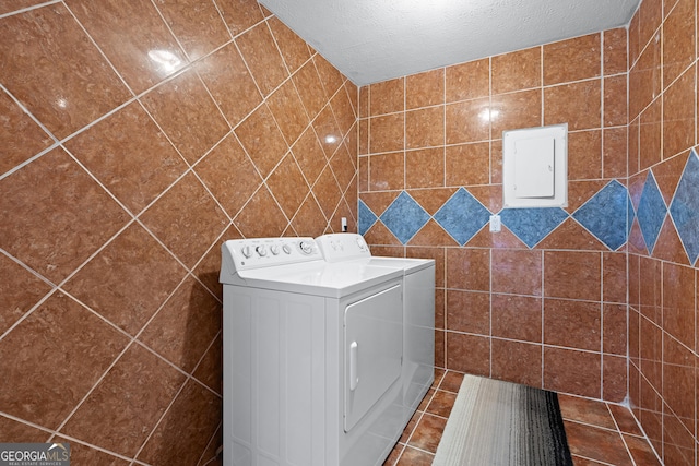 laundry area featuring electric panel, washer and clothes dryer, and a textured ceiling