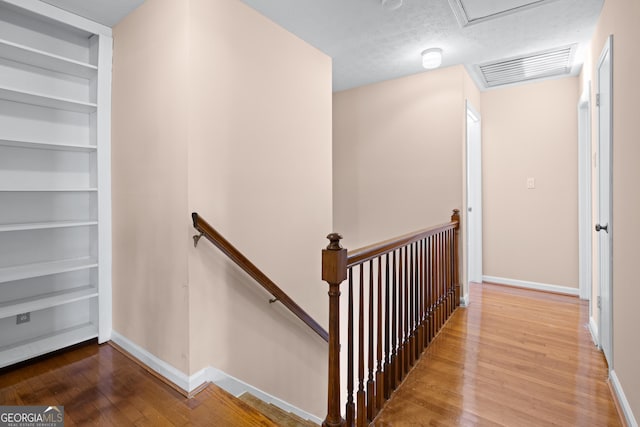 staircase with hardwood / wood-style flooring, built in features, and a textured ceiling