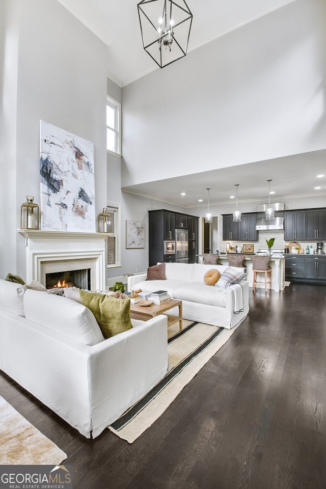 living room with a notable chandelier, a towering ceiling, and dark hardwood / wood-style floors