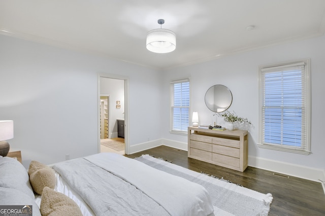 bedroom featuring connected bathroom, crown molding, and dark wood-type flooring