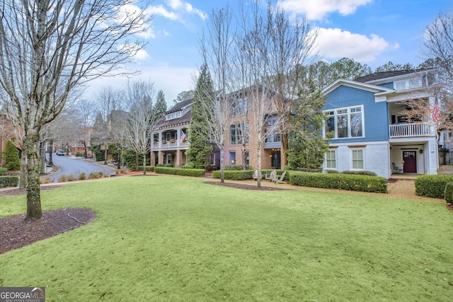 exterior space with a balcony, ceiling fan, and a front lawn