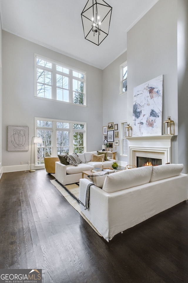 living room with a notable chandelier, dark hardwood / wood-style floors, and a high ceiling