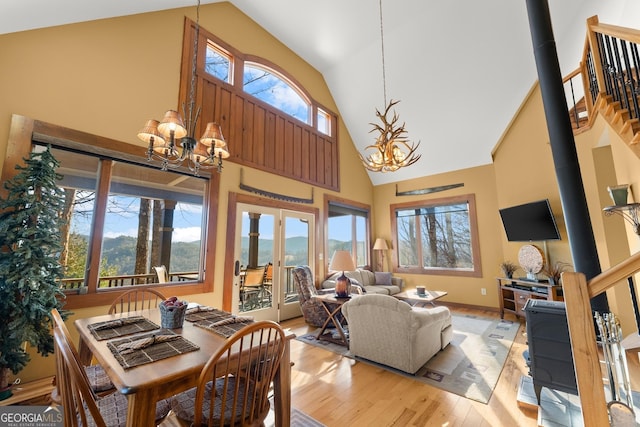 dining area with high vaulted ceiling, french doors, a notable chandelier, and light wood-type flooring