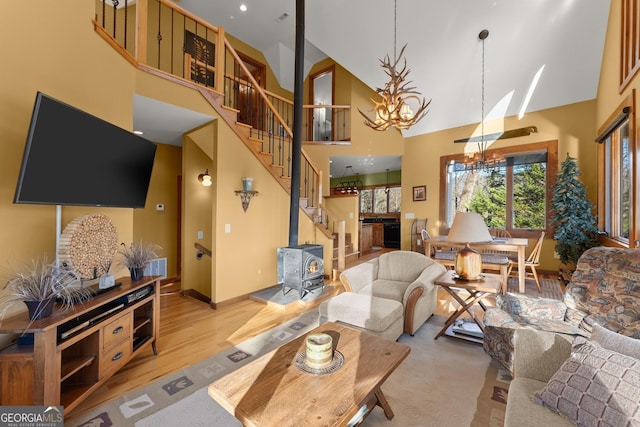 living room featuring a towering ceiling, light hardwood / wood-style flooring, and a wood stove