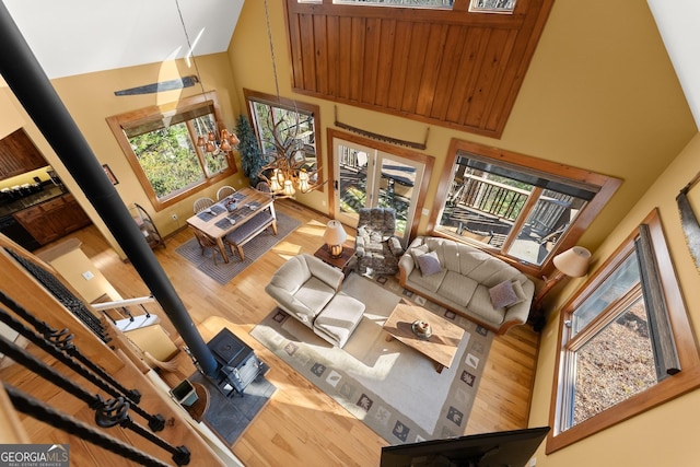 living room with a high ceiling, a wood stove, and wood-type flooring