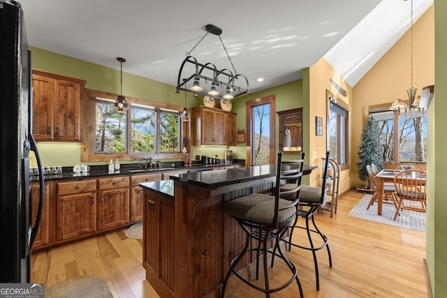 kitchen featuring decorative light fixtures, light hardwood / wood-style floors, a center island, and a breakfast bar area