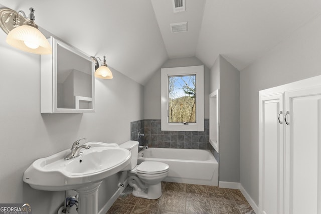 bathroom featuring a tub to relax in, toilet, and vaulted ceiling