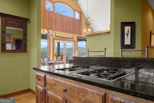 kitchen with stainless steel gas stovetop, vaulted ceiling, decorative light fixtures, a mountain view, and an inviting chandelier