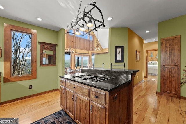 kitchen with a kitchen island, light hardwood / wood-style floors, dark stone counters, and stainless steel gas cooktop