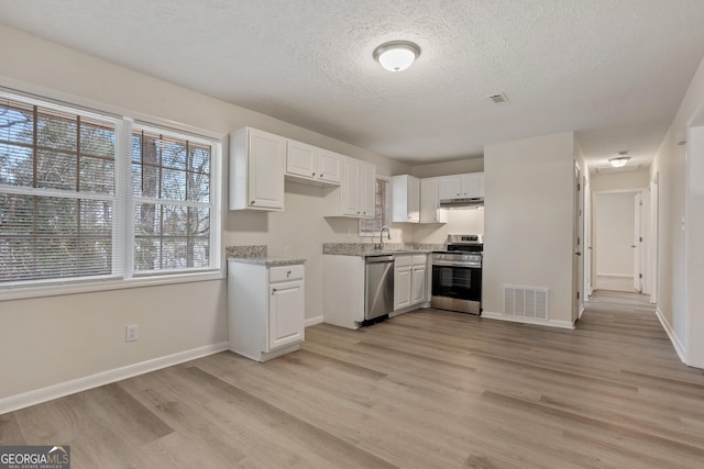 kitchen featuring white cabinetry, sink, light hardwood / wood-style flooring, stainless steel appliances, and light stone counters