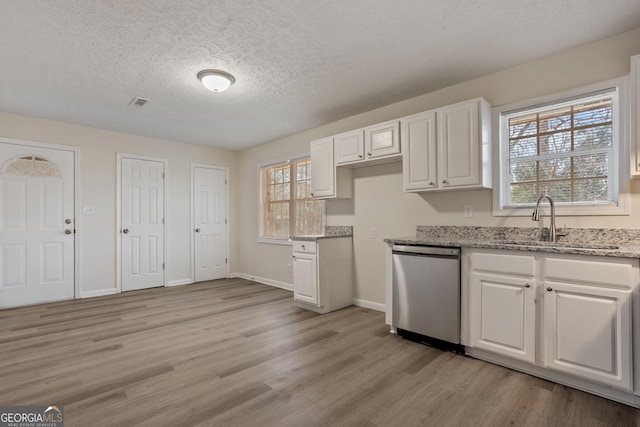 kitchen featuring light stone countertops, a textured ceiling, white cabinets, dishwasher, and sink