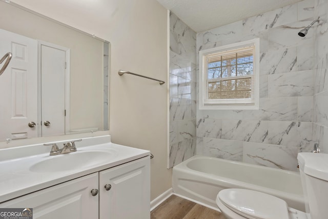 full bathroom featuring a textured ceiling, tiled shower / bath combo, vanity, toilet, and hardwood / wood-style flooring