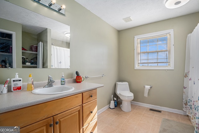 bathroom with vanity, toilet, and a textured ceiling