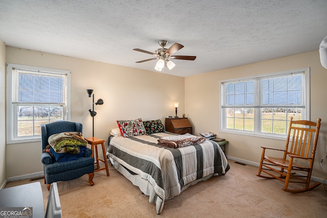 carpeted bedroom featuring ceiling fan and a textured ceiling