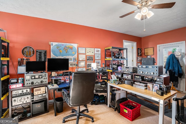 carpeted home office with ceiling fan and a textured ceiling