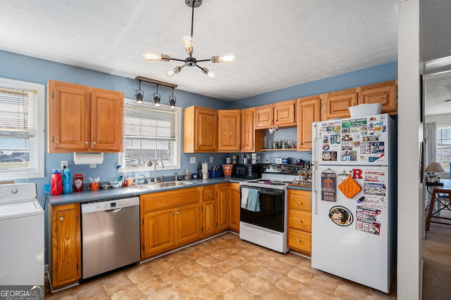 kitchen featuring decorative light fixtures, a wealth of natural light, white appliances, and washer / clothes dryer