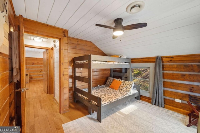 bedroom featuring wood ceiling, light hardwood / wood-style flooring, ceiling fan, wood walls, and lofted ceiling