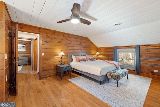 bedroom featuring vaulted ceiling, wooden ceiling, wooden walls, light wood-type flooring, and ceiling fan