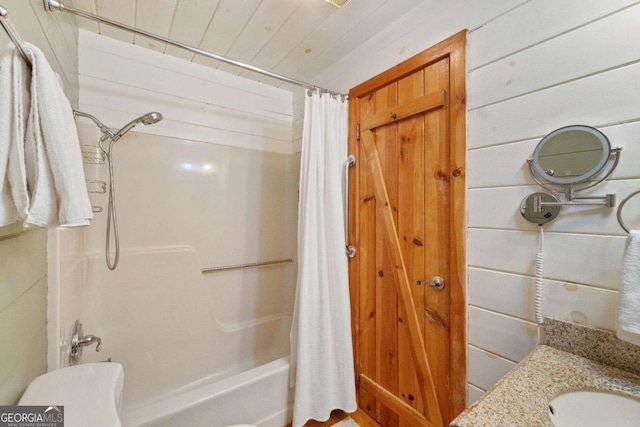 bathroom featuring vanity, wooden walls, and shower / bath combo with shower curtain