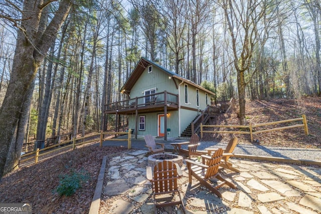 back of property featuring a wooden deck, an outdoor fire pit, and a patio