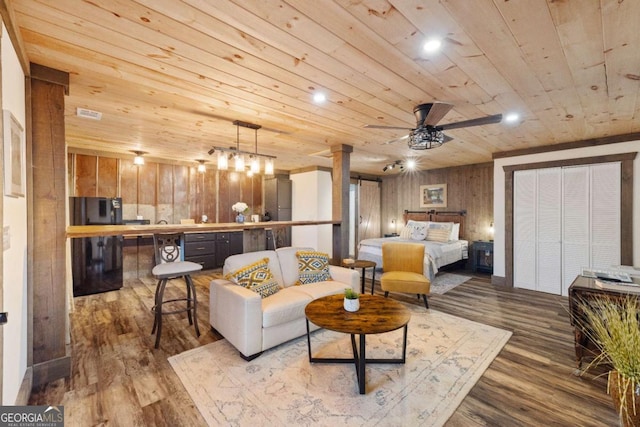 living room with wood-type flooring, ceiling fan, ornate columns, wooden ceiling, and wood walls