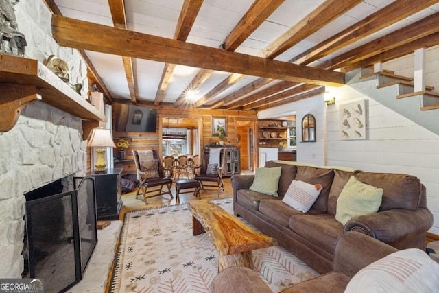 living room featuring beam ceiling, wood walls, and a fireplace