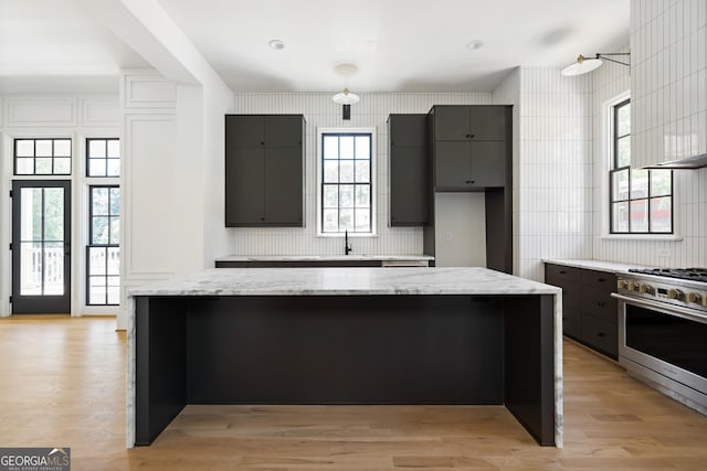 kitchen with stainless steel range with gas cooktop, a center island, sink, and light wood-type flooring