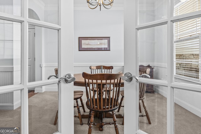 dining room featuring a chandelier, carpet floors, french doors, and ornamental molding