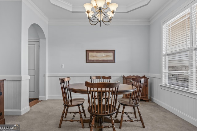 carpeted dining space with a chandelier, crown molding, and a tray ceiling