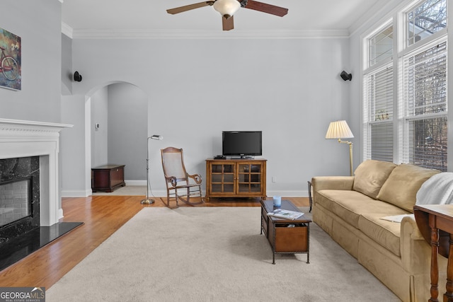 living room with light wood-type flooring, ceiling fan, and crown molding